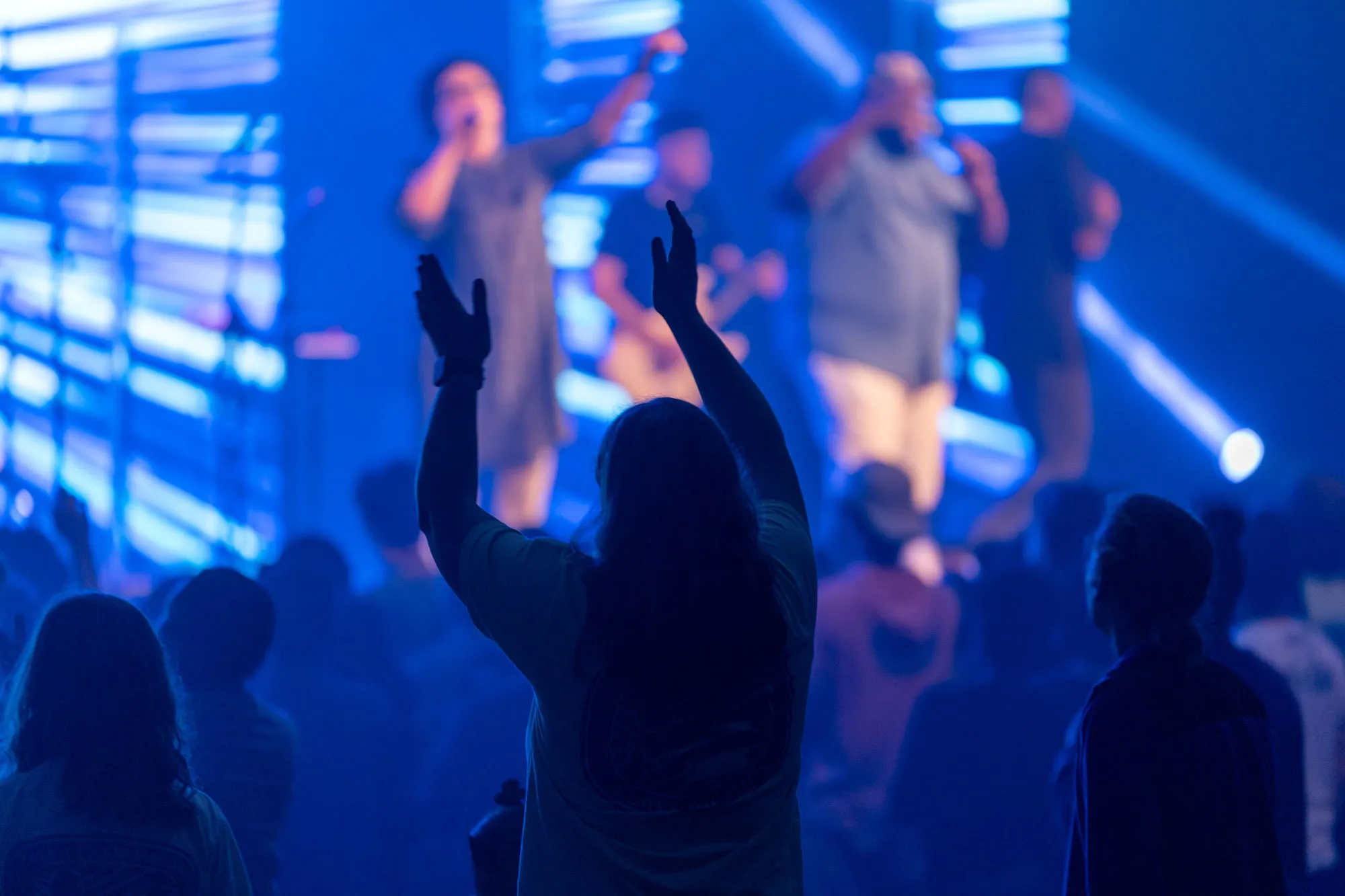 Students worshiping with hands raised during a night service at Summer Surge